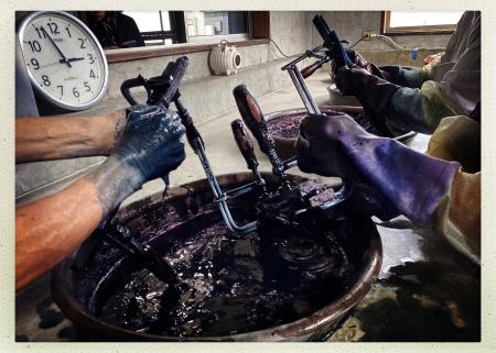 Dipping folded and clamped fabric into the indigo bath at Takarajima Senkou studio